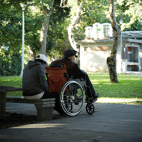 Caregiver assisting with household tasks for an elderly man in a wheelchair, promoting Supported Independent Living (SIL) under NDIS Disability Support Provider in - Melbourne